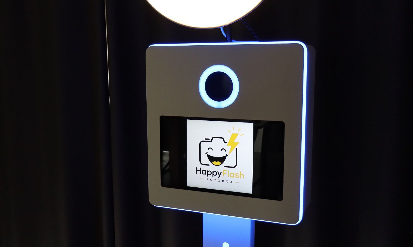 Detailaufnahme der HappyFlash Fotobox mit blau beleuchtetem Ring und Display