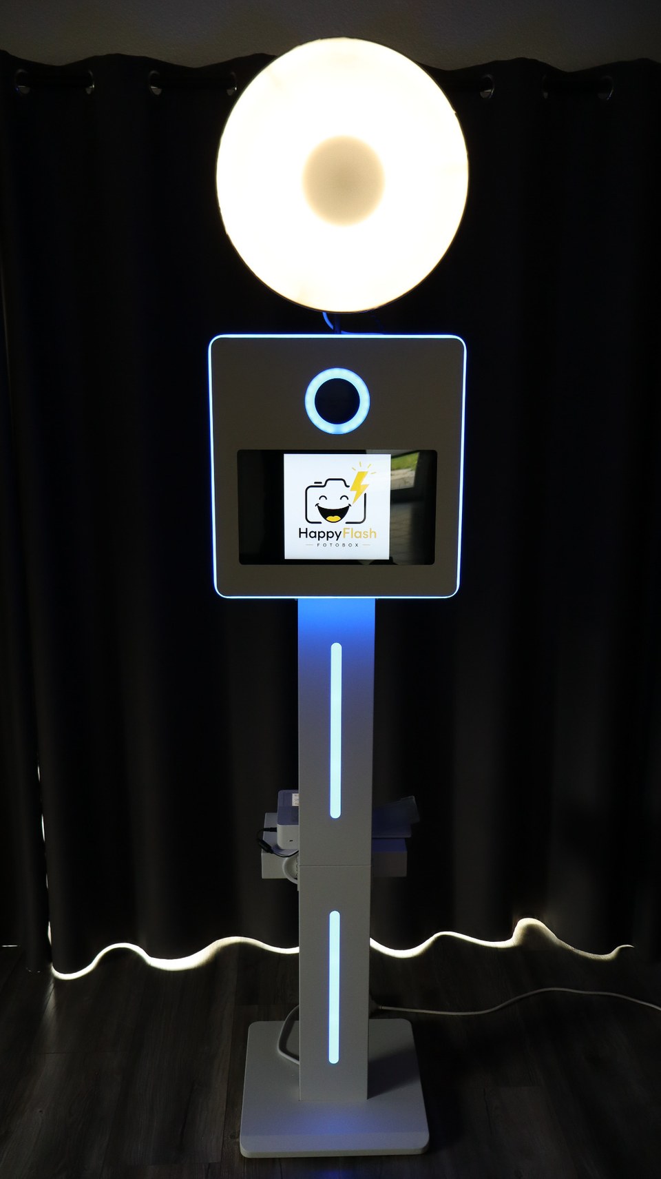 Komplettaufnahme der HappyFlash Fotobox mit blau beleuchteten LED-Elementen vor dunklem Hintergrund